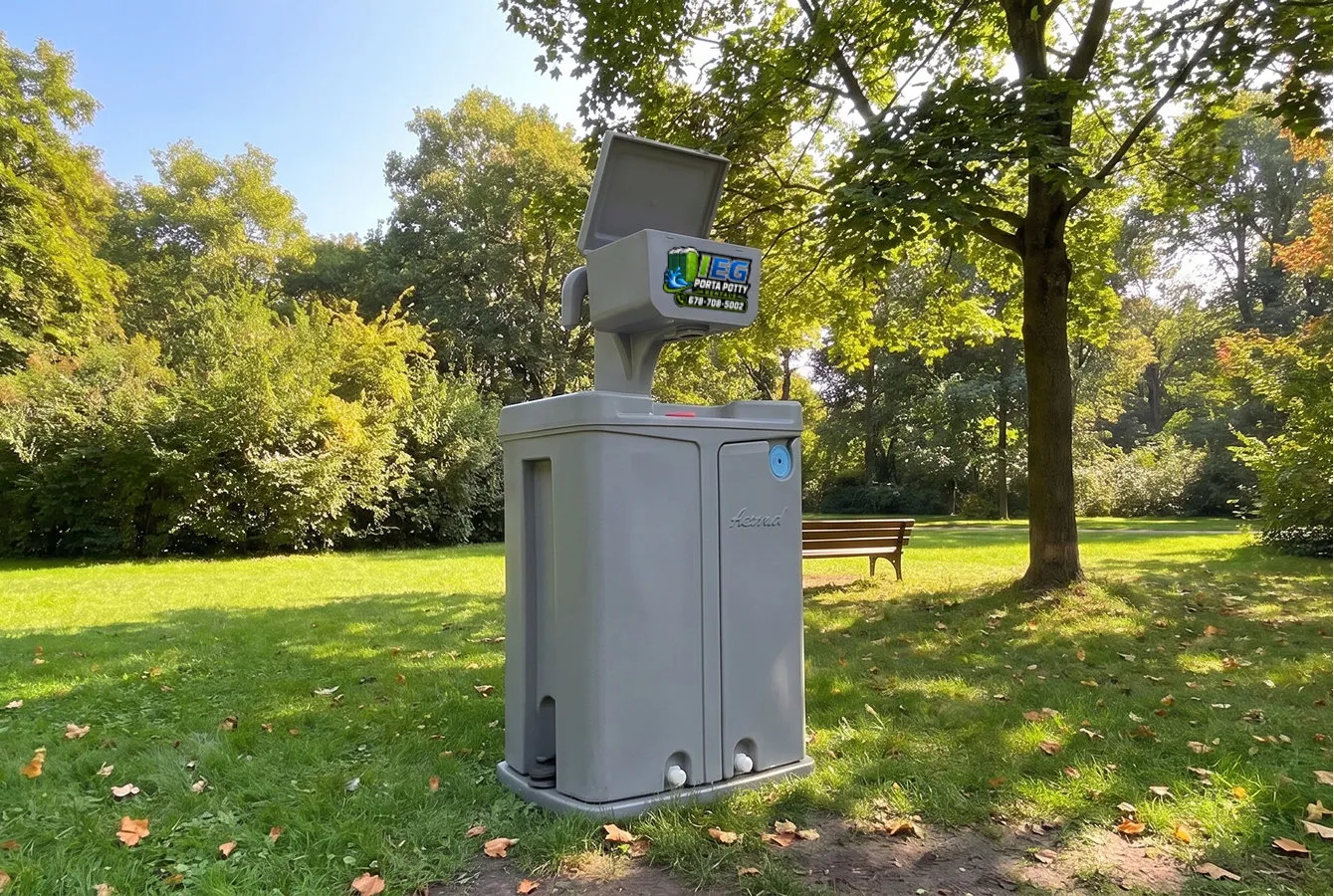 A freestanding portable hand washing station with a foot-pump sink set up on grass in a park.