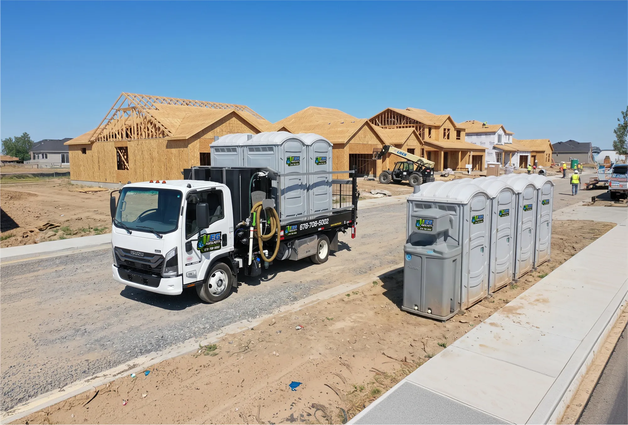 Portable restrooms lined up beside a site office trailer at a construction site.